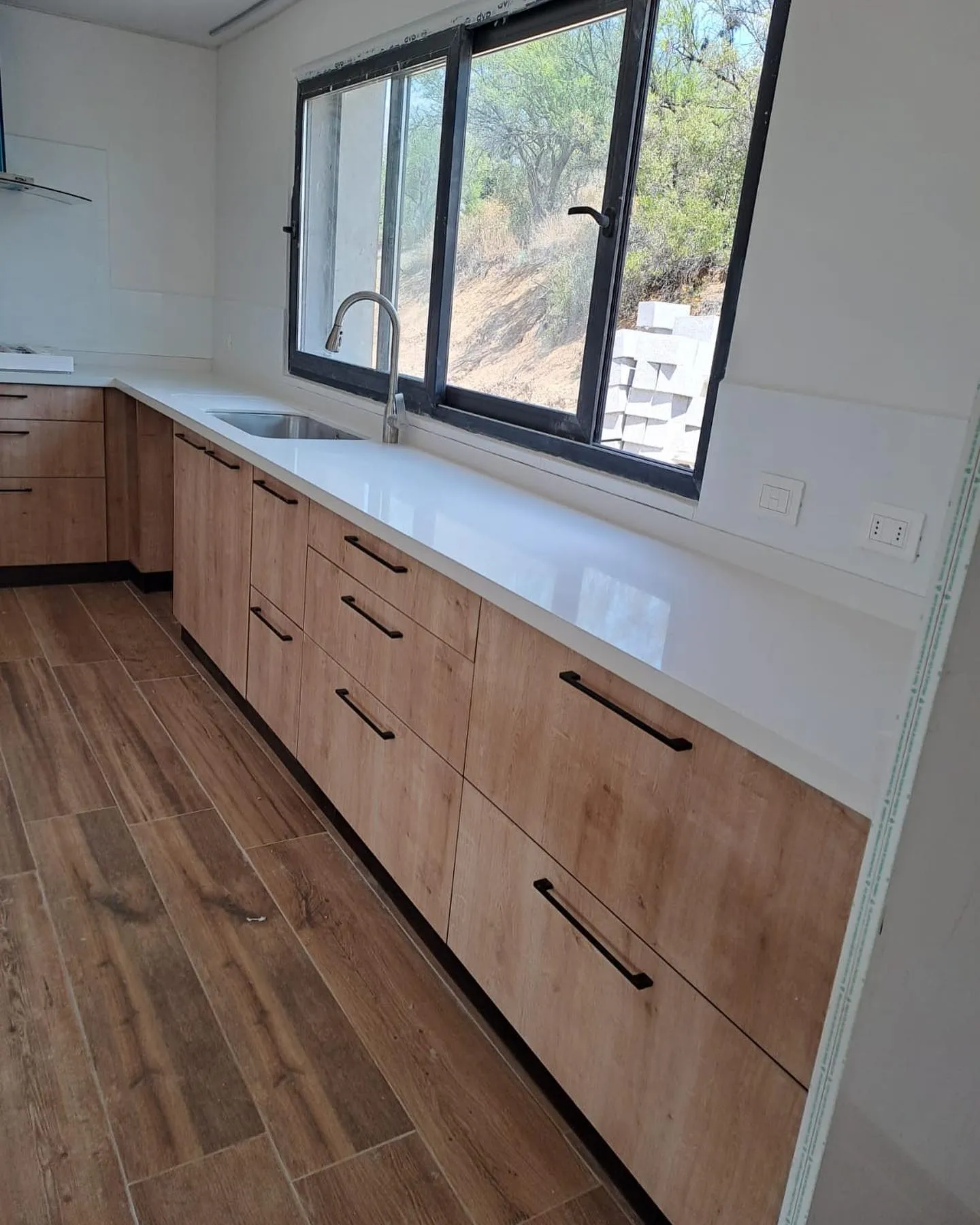 Cocina con iluminación y muebles de madera con cubierta blanca